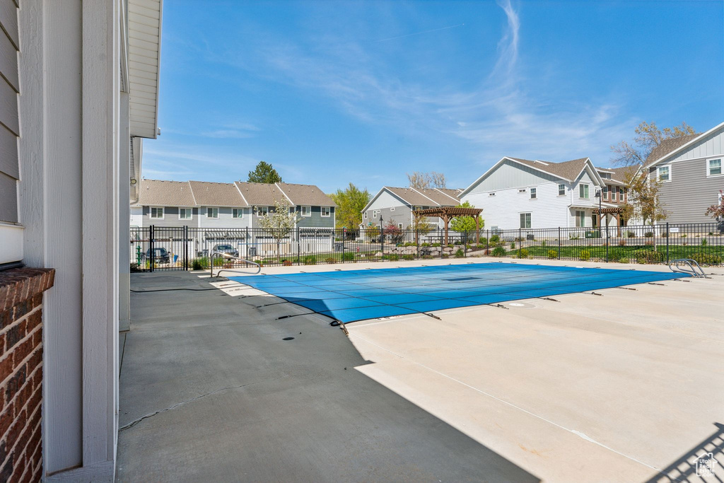 Pool with a patio, fence, and a residential view