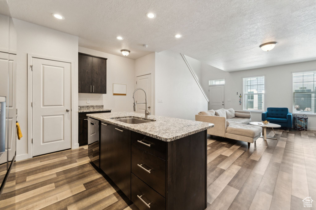 Kitchen with a textured ceiling, wood finished floors, recessed lighting, and a sink