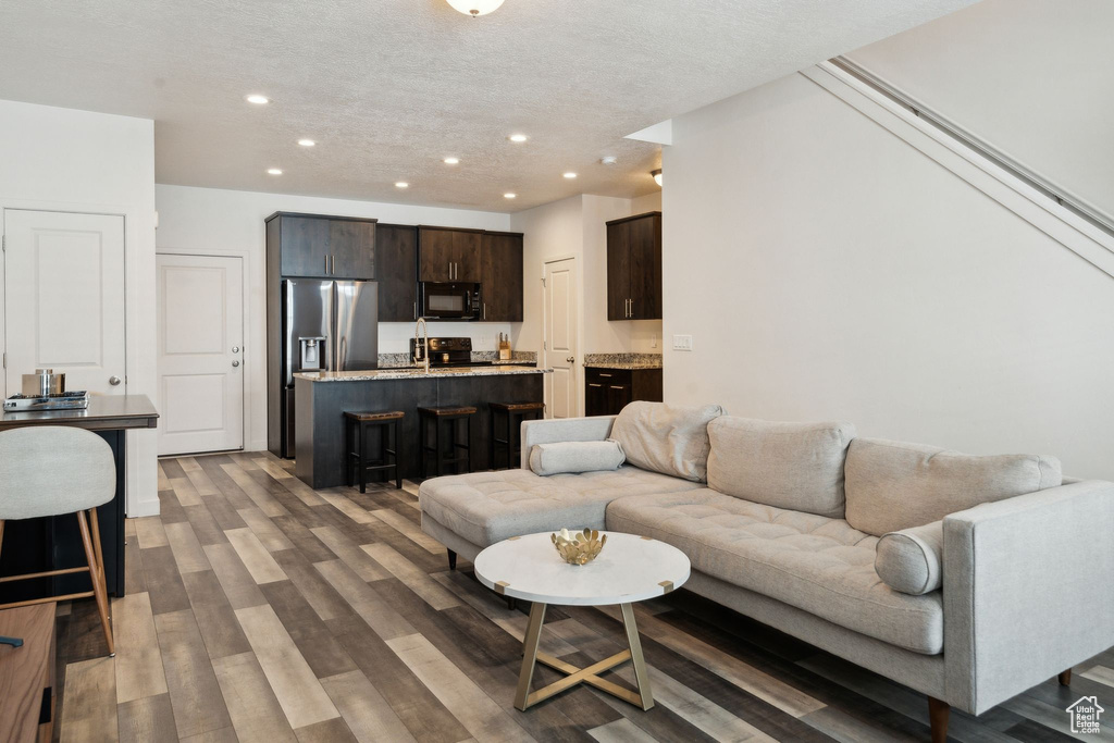 Living area featuring recessed lighting, a textured ceiling, and wood finished floors