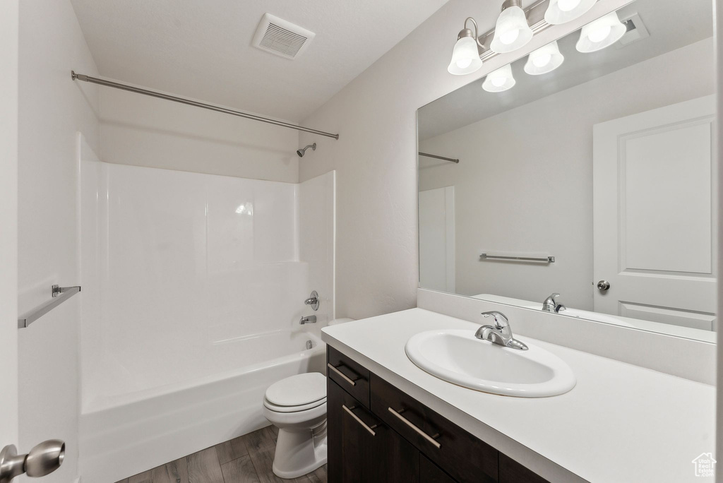 Full bathroom featuring visible vents, vanity, shower / bathtub combination, wood finished floors, and toilet