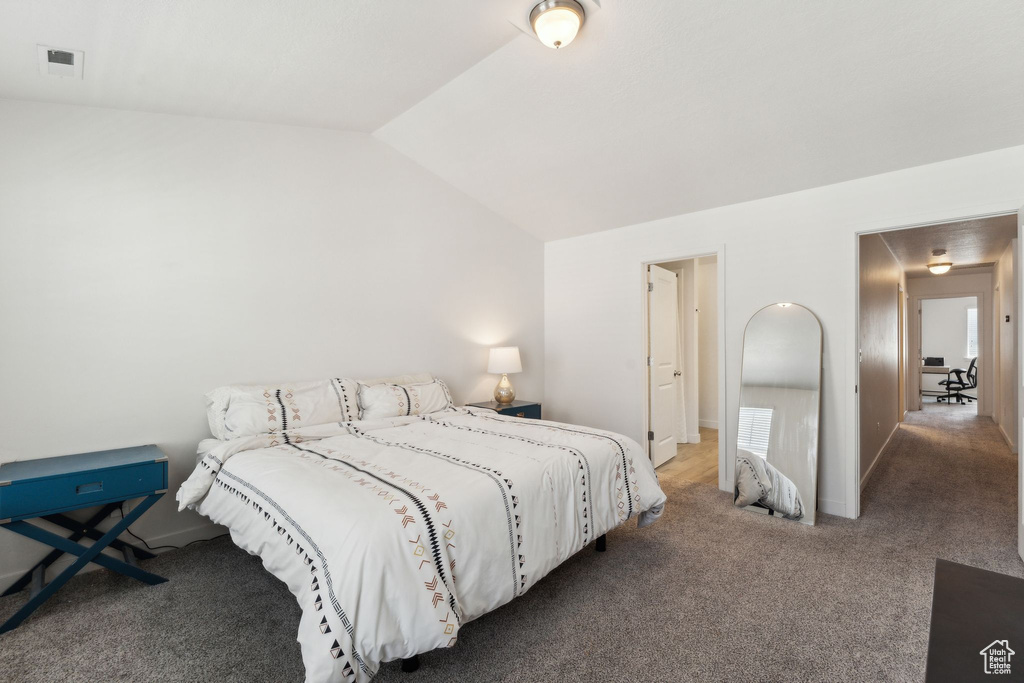 Carpeted bedroom featuring visible vents, vaulted ceiling, and baseboards