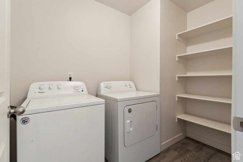 Clothes washing area with dark wood-style floors, baseboards, laundry area, and washer and clothes dryer