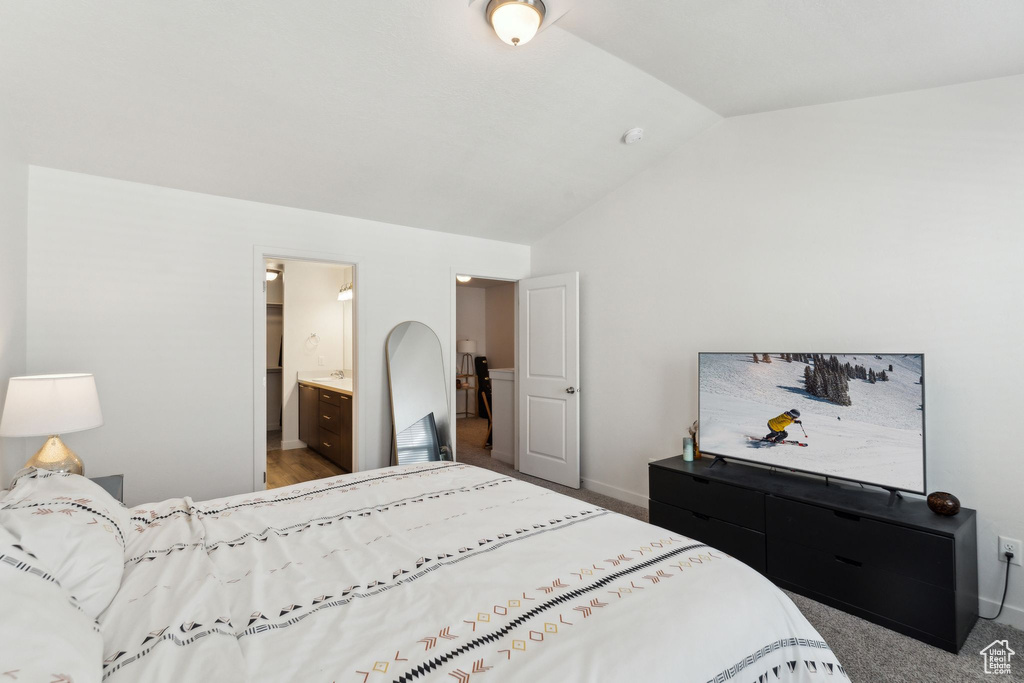 Bedroom featuring baseboards, ensuite bathroom, and vaulted ceiling