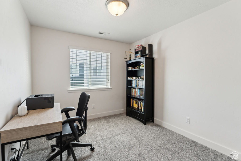 Office space with baseboards, visible vents, and light colored carpet