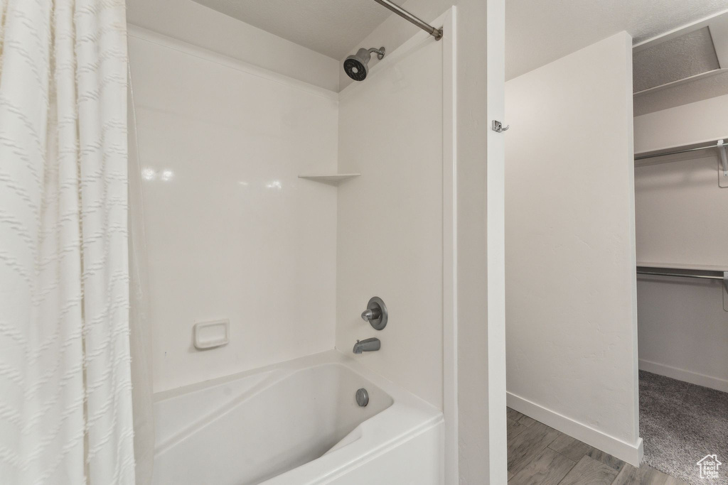 Full bath with shower / bath combo with shower curtain, wood finished floors, and baseboards