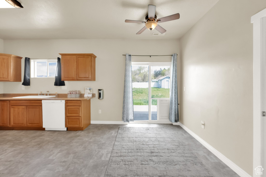 Kitchen with a sink, light countertops, a ceiling fan, baseboards, and dishwasher