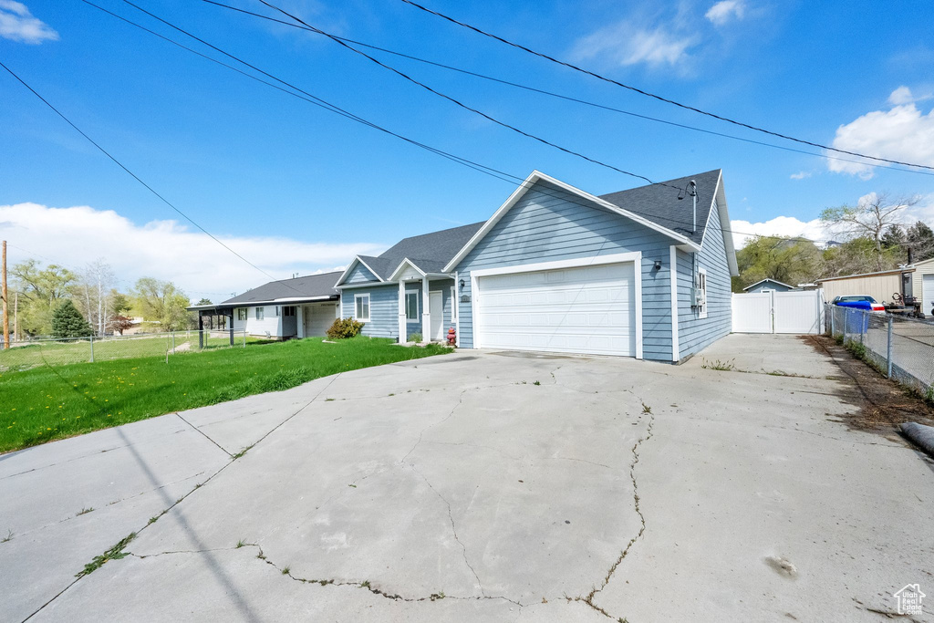 Ranch-style house featuring driveway, fence, a front lawn, and an attached garage