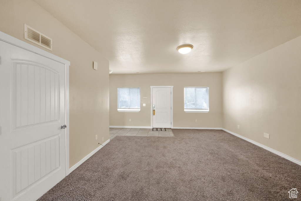 Carpeted empty room featuring visible vents and baseboards
