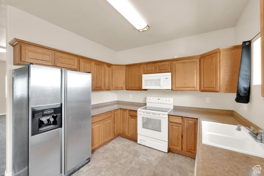 Kitchen featuring light countertops, a sink, and white appliances