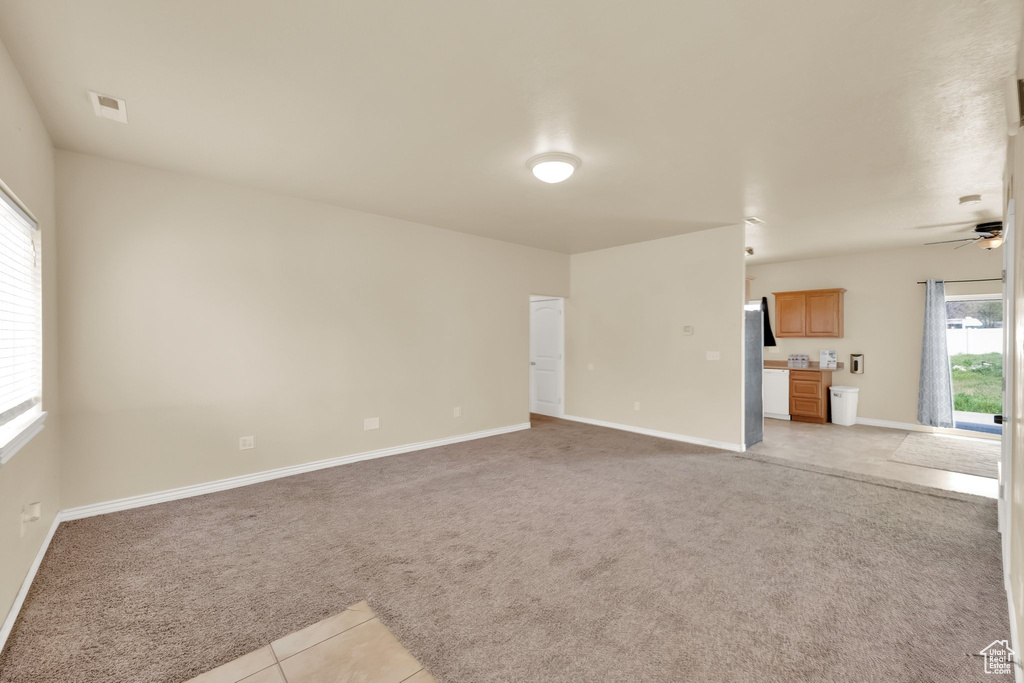 Unfurnished living room with ceiling fan, baseboards, light colored carpet, and plenty of natural light