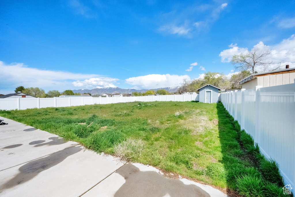 View of yard featuring an outbuilding, a shed, a fenced backyard, and a mountain view