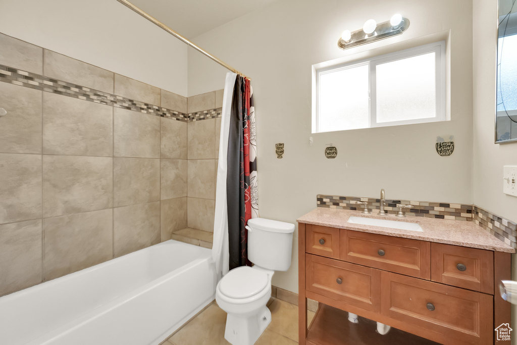 Bathroom with a healthy amount of sunlight, toilet, shower / bath combination with curtain, and vanity