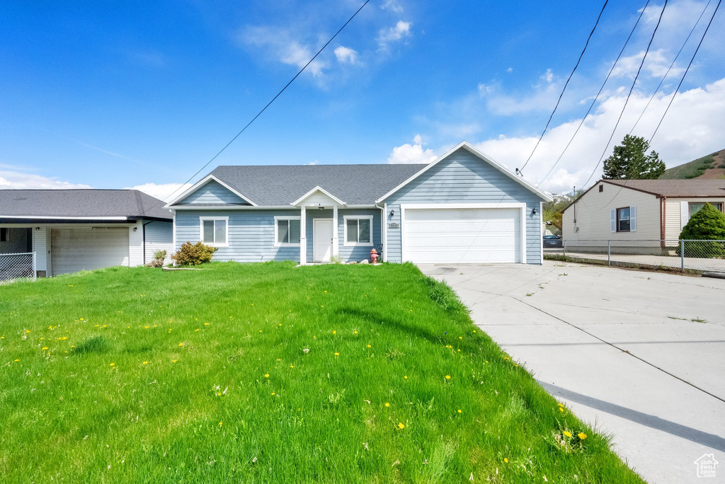Ranch-style home featuring a garage, fence, a front lawn, and concrete driveway