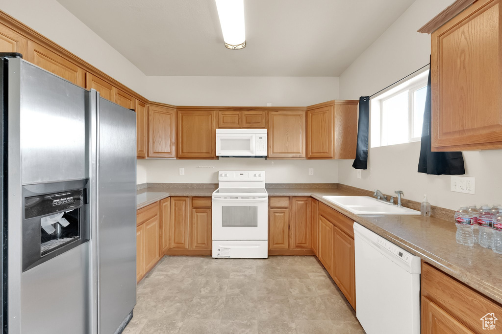 Kitchen with white appliances, light countertops, and a sink