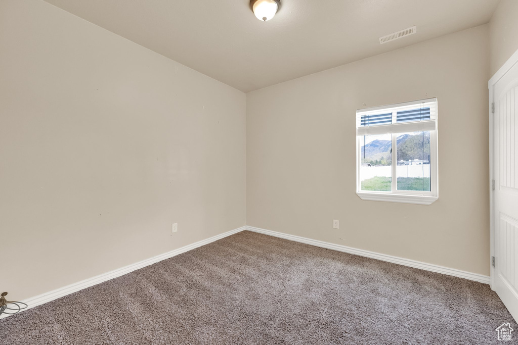 Carpeted spare room featuring baseboards and visible vents