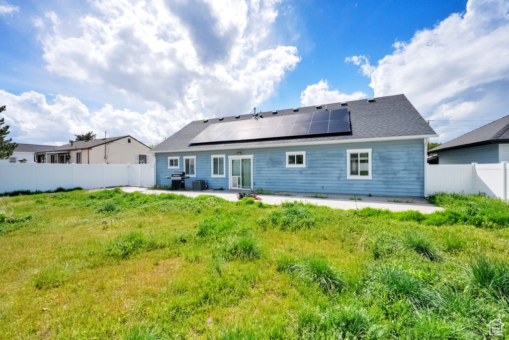 Back of house featuring a patio area, solar panels, and a fenced backyard