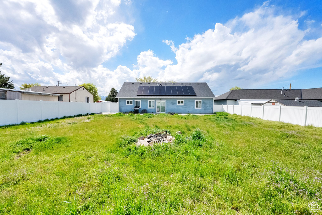 Back of house featuring a lawn, solar panels, and a fenced backyard