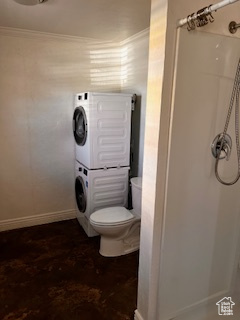 Bathroom featuring stacked washer and clothes dryer, walk in shower, toilet, baseboards, and ornamental molding