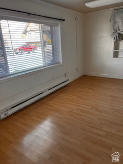 Spare room featuring a healthy amount of sunlight, baseboards, baseboard heating, and light wood-style floors