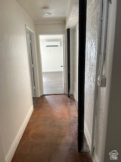 Hall featuring concrete floors, a wall mounted AC, and baseboards