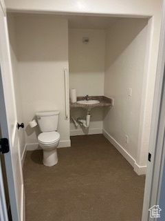 Half bathroom featuring toilet, a sink, and baseboards
