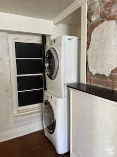 Clothes washing area with stacked washer / drying machine, laundry area, and baseboards