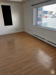 Spare room featuring light wood finished floors, a baseboard heating unit, and baseboards