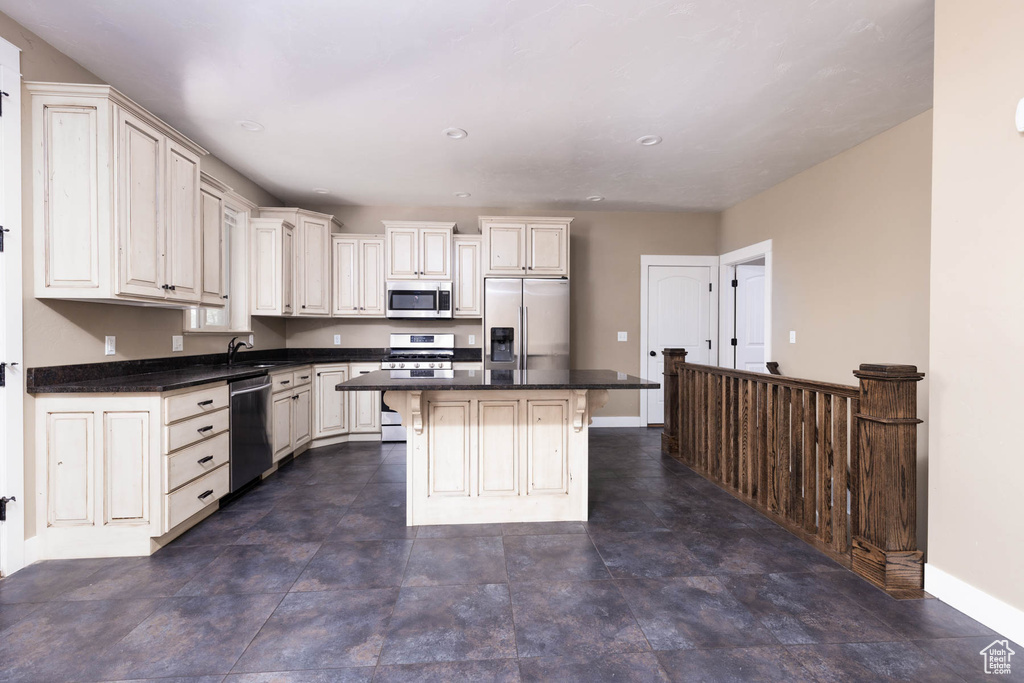 Kitchen featuring stainless steel appliances, baseboards, a sink, a kitchen bar, and a center island