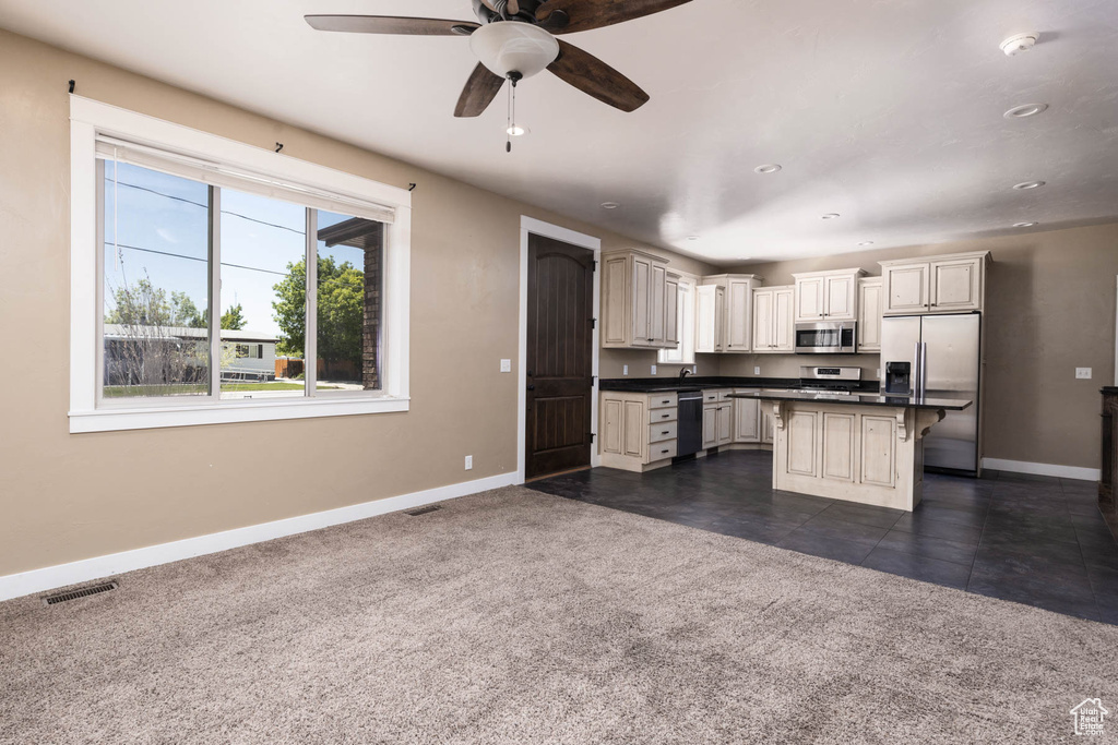 Kitchen featuring appliances with stainless steel finishes, baseboards, a kitchen breakfast bar, dark countertops, and a ceiling fan
