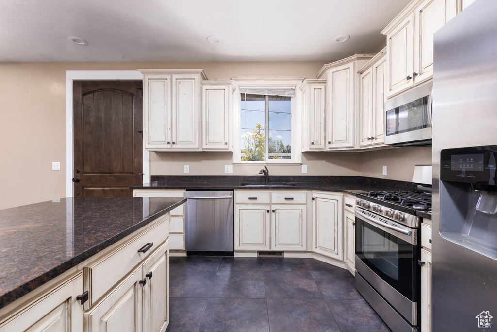 Kitchen featuring appliances with stainless steel finishes, a sink, recessed lighting, and dark stone counters