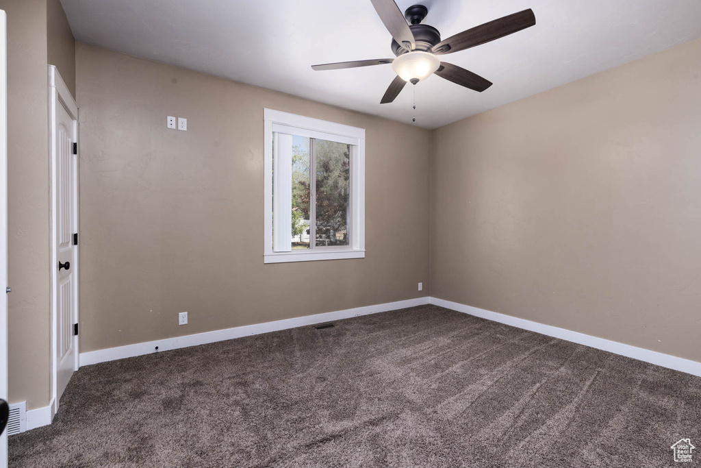 Unfurnished room featuring dark carpet, a ceiling fan, and baseboards