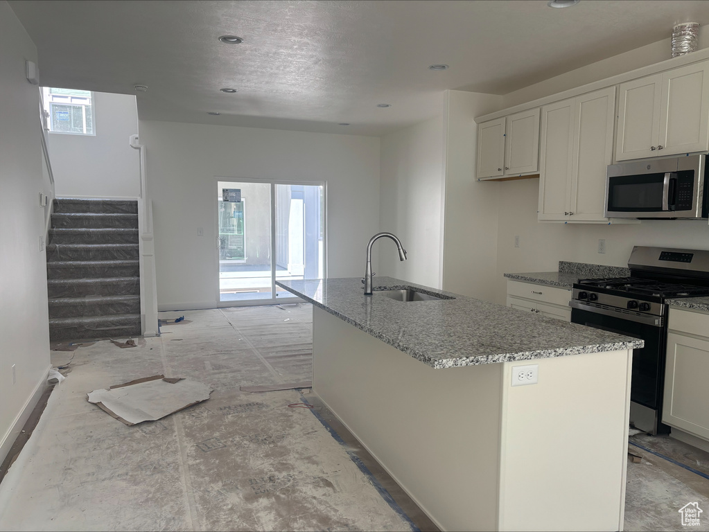 Kitchen with plenty of natural light, a sink, light stone counters, and stainless steel appliances