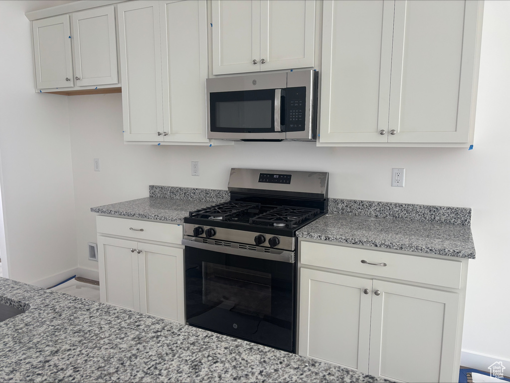 Kitchen featuring baseboards, appliances with stainless steel finishes, and light stone countertops