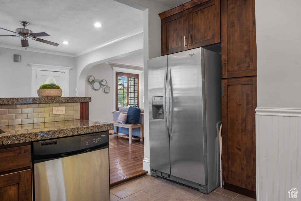 Kitchen featuring appliances with stainless steel finishes, ornamental molding, a ceiling fan, light tile patterned floors, and dark brown cabinetry