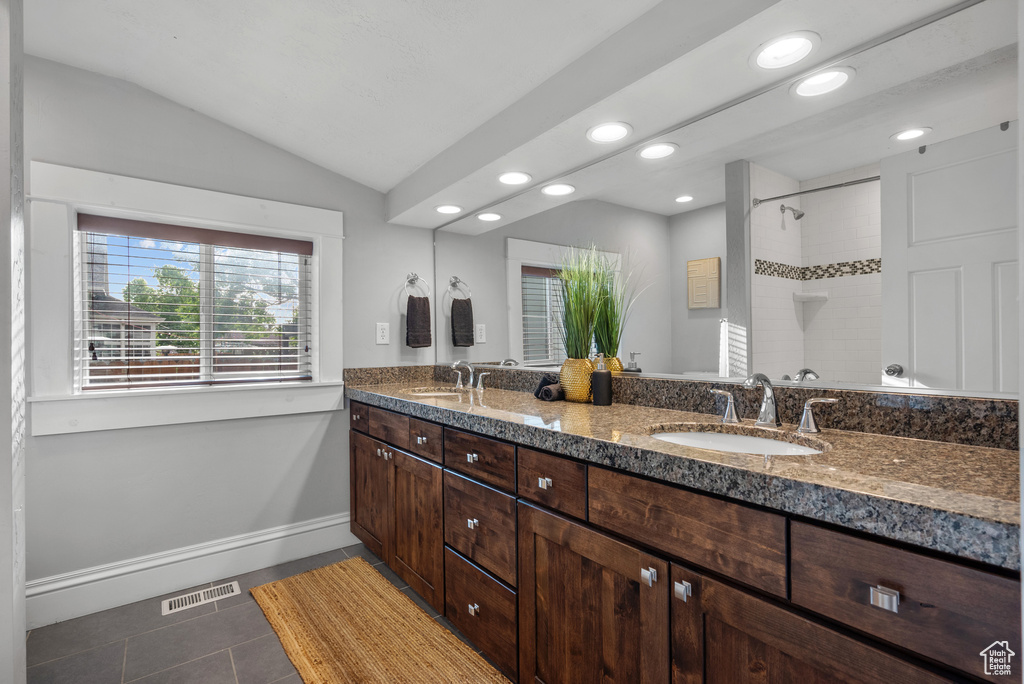 Full bathroom with double vanity, tile patterned floors, recessed lighting, tiled shower, and baseboards