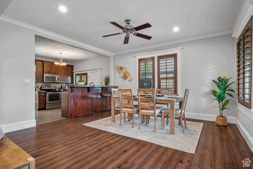 Dining room featuring dark wood-type flooring, a ceiling fan, baseboards, recessed lighting, and ornamental molding