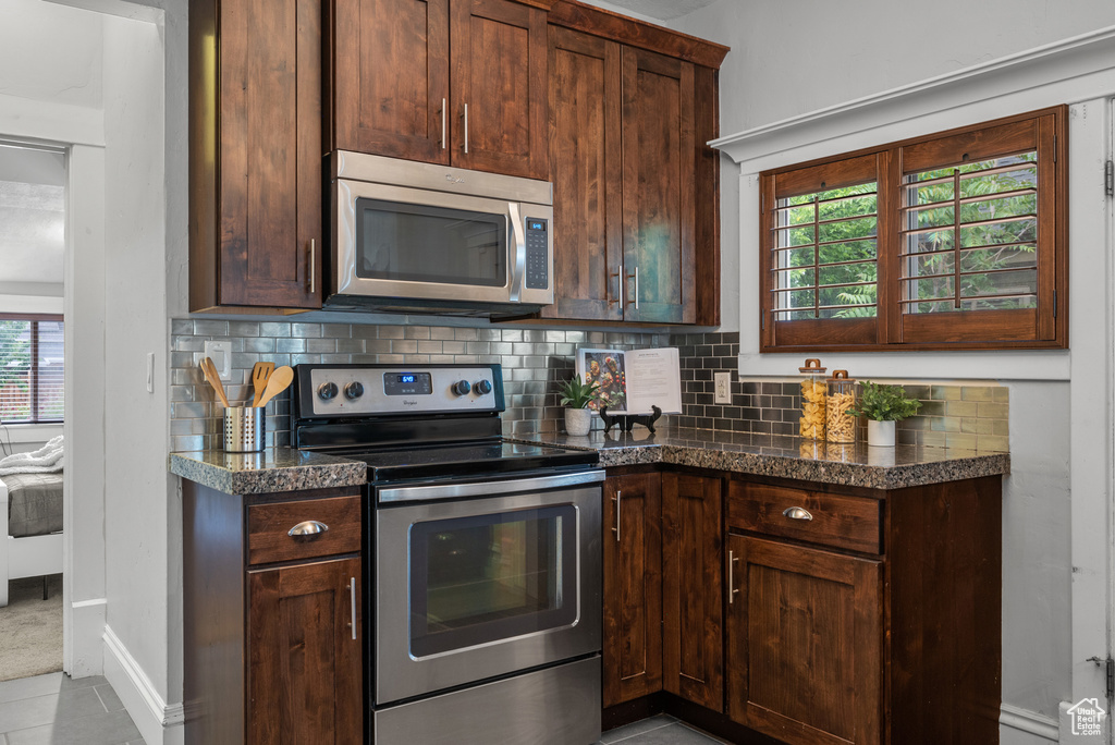 Kitchen featuring appliances with stainless steel finishes, backsplash, and dark countertops