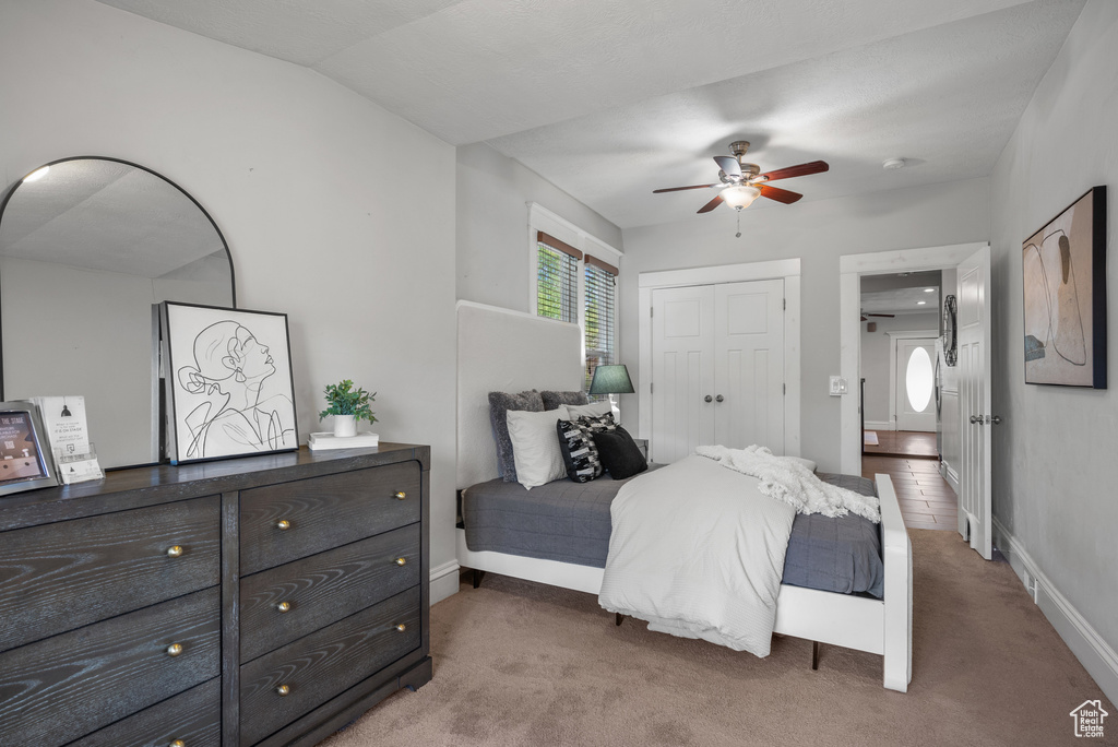 Bedroom with light colored carpet, a closet, baseboards, and ceiling fan