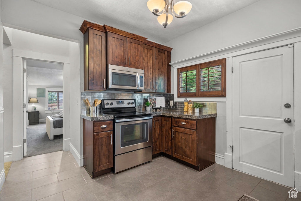 Kitchen featuring appliances with stainless steel finishes, decorative backsplash, healthy amount of natural light, and dark brown cabinetry