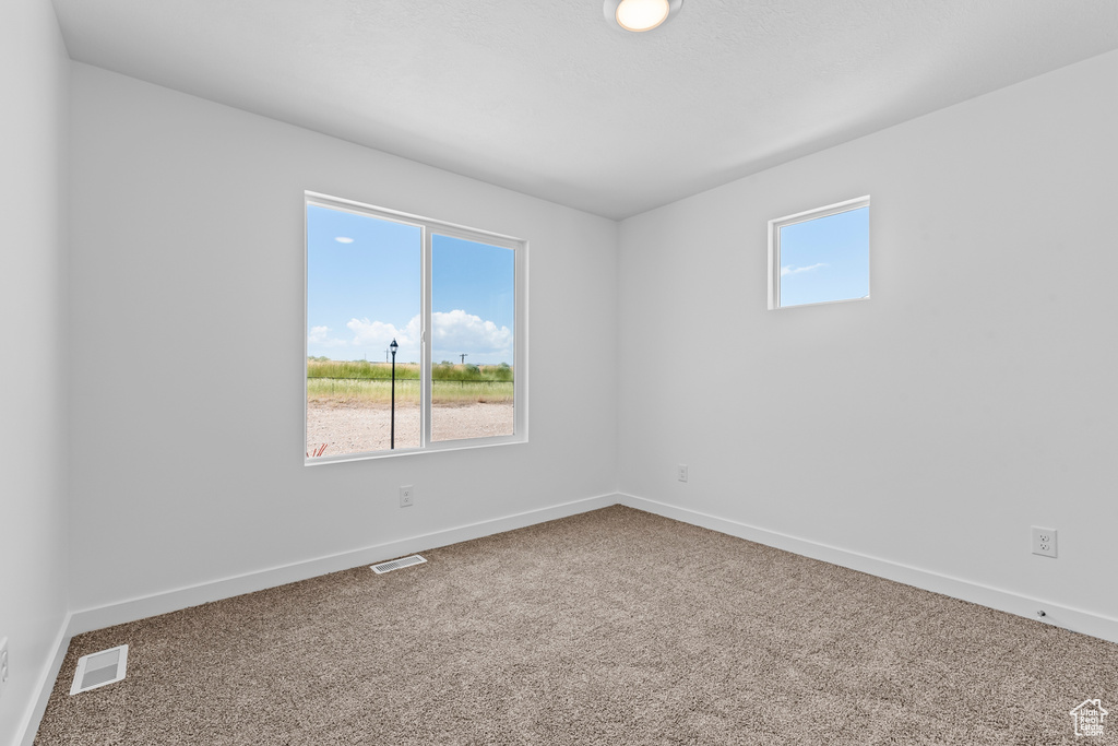 Unfurnished room with carpet, visible vents, and baseboards