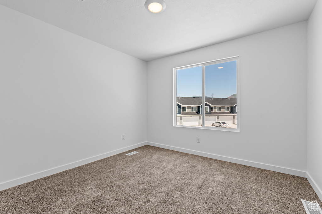 Carpeted empty room featuring visible vents and baseboards