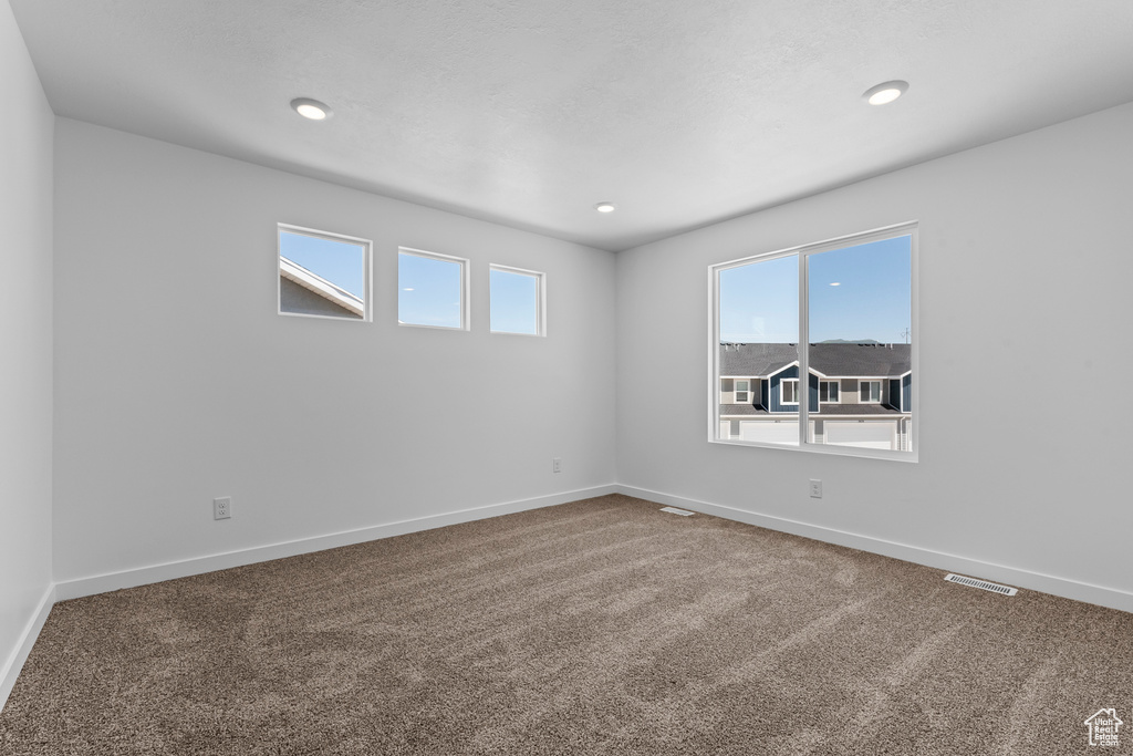 Carpeted spare room featuring recessed lighting, visible vents, and baseboards