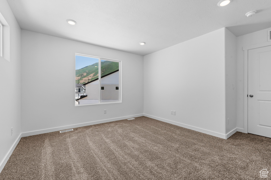 Carpeted spare room with baseboards, visible vents, and recessed lighting