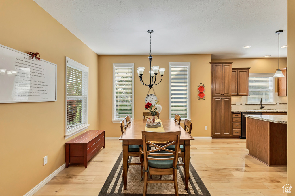 Dining space with an inviting chandelier, recessed lighting, light wood-style flooring, and baseboards