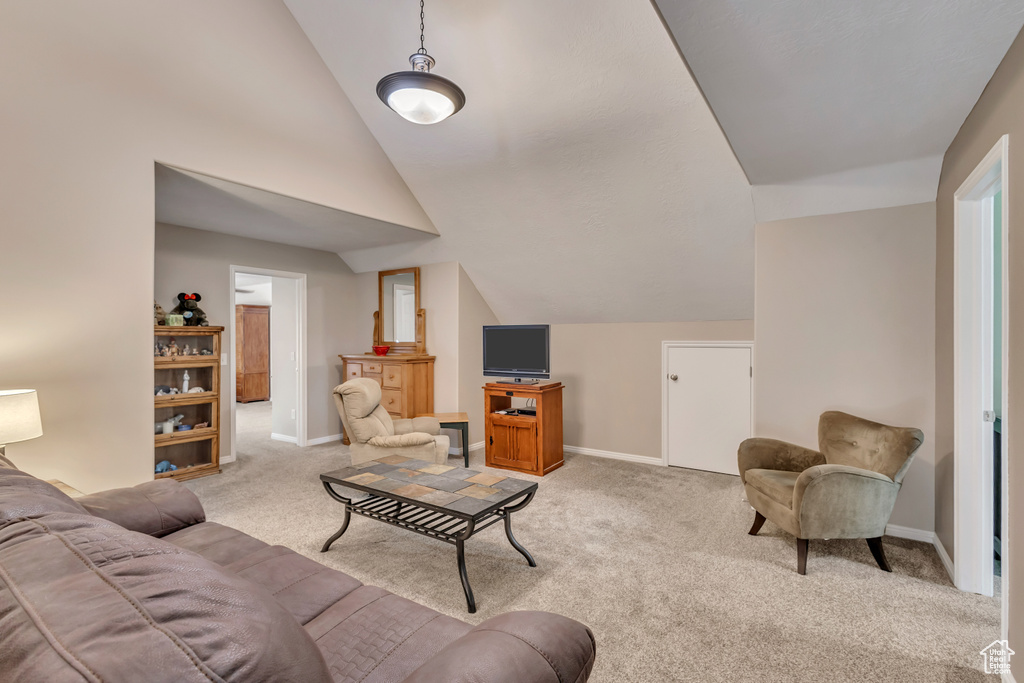 Living room with baseboards, vaulted ceiling, and light carpet