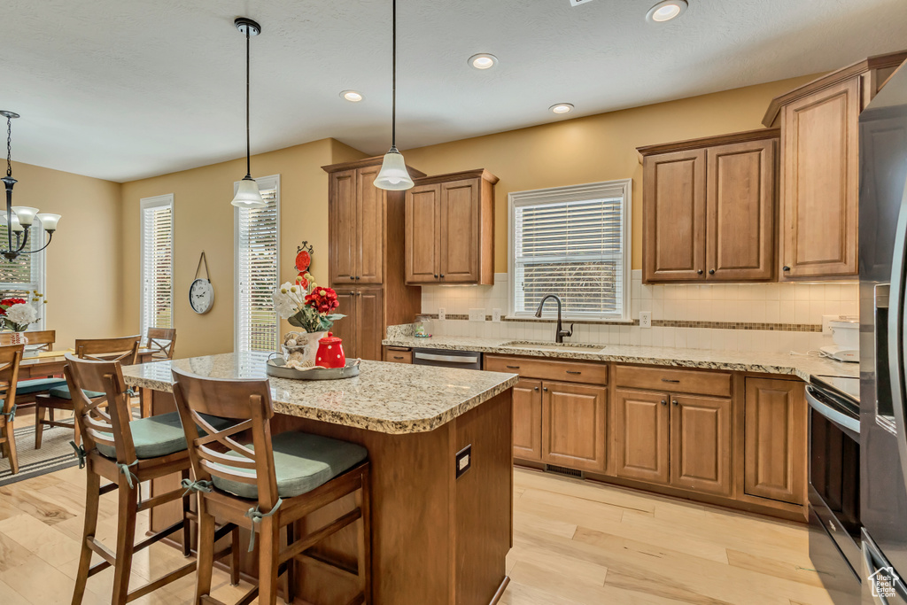 Kitchen with appliances with stainless steel finishes, a center island, light wood-style flooring, and a sink