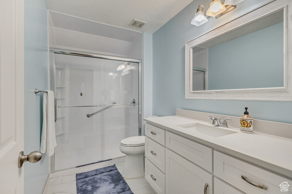 Full bath with a shower stall, marble finish floor, toilet, vanity, and visible vents
