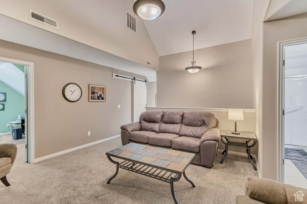 Living area featuring visible vents, a barn door, and carpet floors