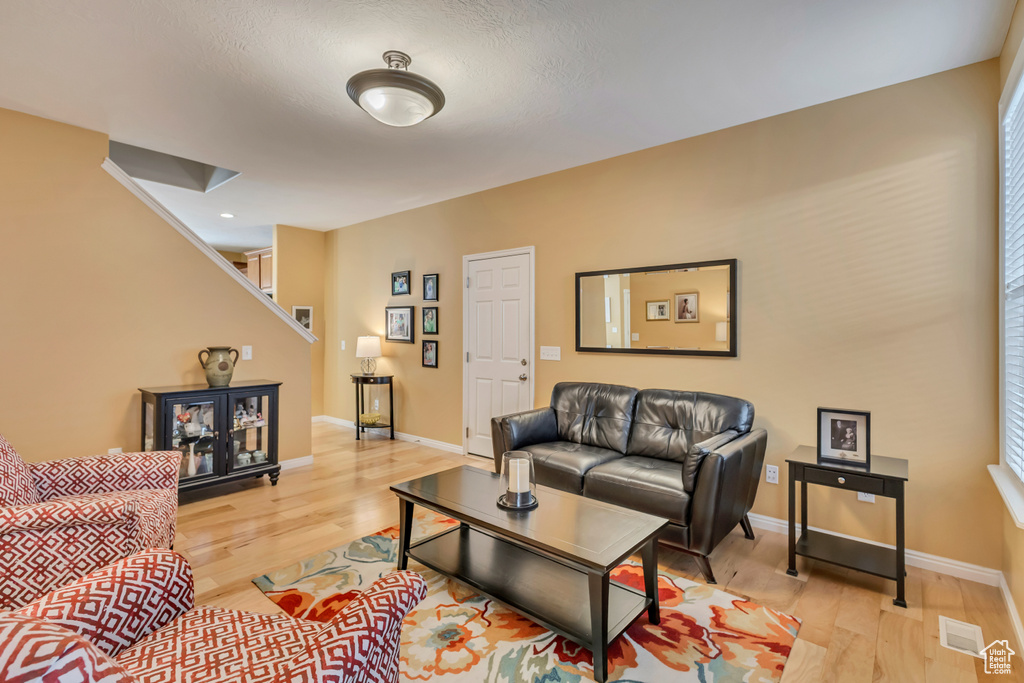Living area featuring baseboards, visible vents, light wood-type flooring, and stairway