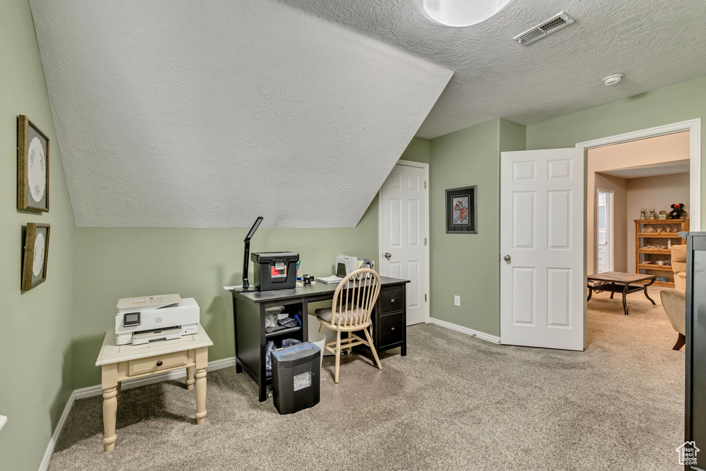 Carpeted home office featuring a textured ceiling, visible vents, and baseboards